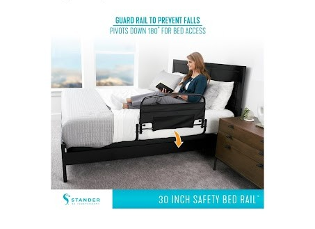 Woman using a safety bed rail in a bedroom setting with 'Stander' branding.