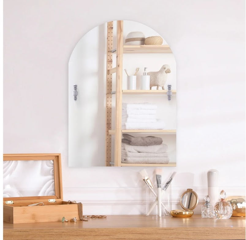 Wooden vanity with mirror and various items on a white wall background