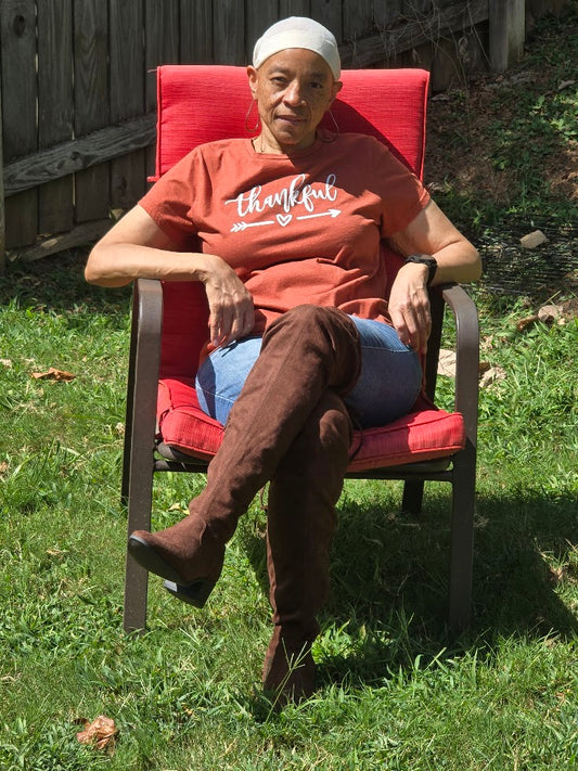 Person sitting in a red chair outdoors wearing chocolate brown over the knee boots