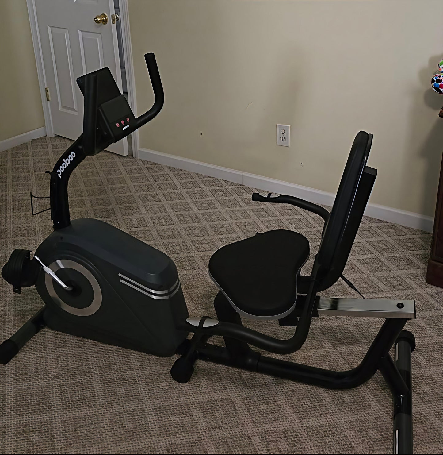Exercise bike on a carpeted floor in a room with beige walls.