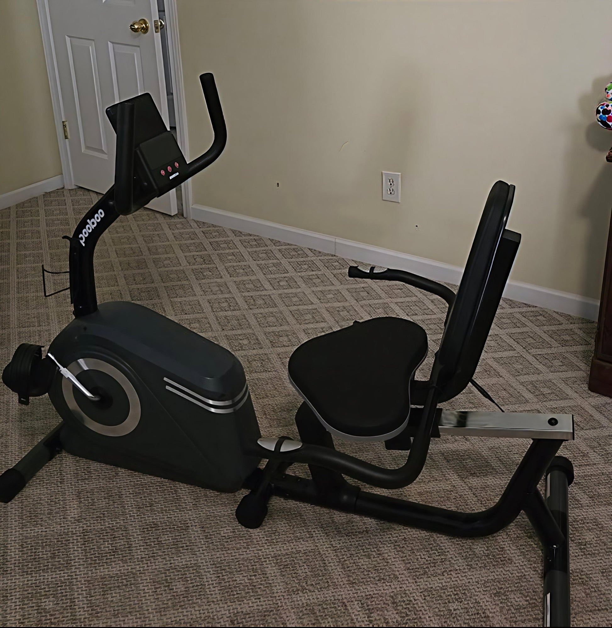Exercise bike on a carpeted floor in a room with beige walls.