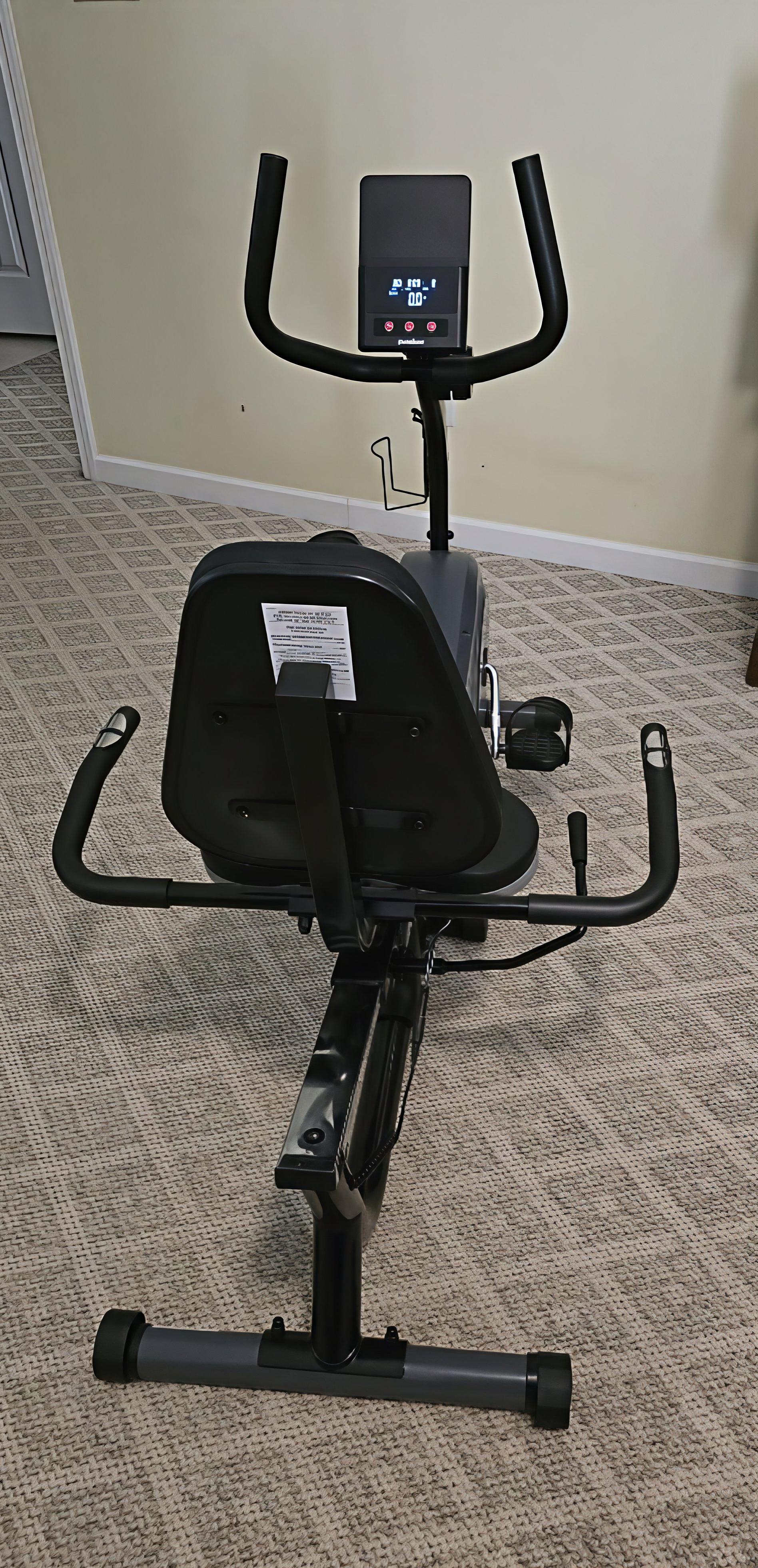 Stationary bike on a carpeted floor with a beige wall in the background